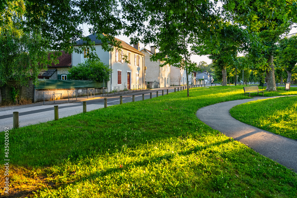 Public park at sunset with large trees in the French town of Morlaas,