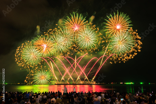 PATTAYA, CHONBURI, THAILAND Beautiful colorful fireworks night scene at Pattaya International Fireworks Festival and silhouette Group of tourist take pictures of firework show on the beach,. photo