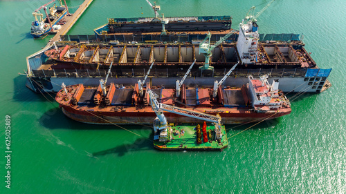 container ship repairing and maintenance on shipyard dry dock in green sea, aerial view © SHUTTER DIN