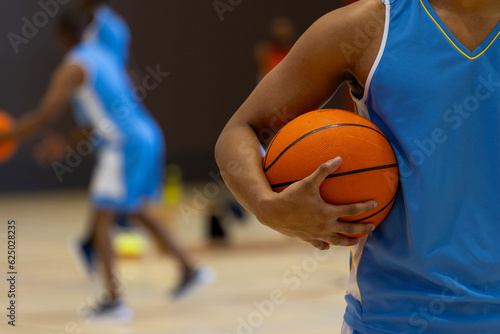 Diverse male basketball players wearing blue sports clothes and playing basketball at gym © wavebreak3