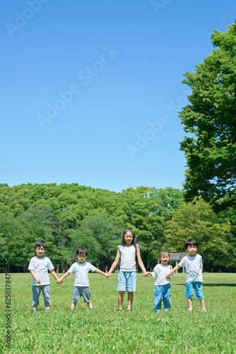 草原で手を繋いで並ぶ子どもたち