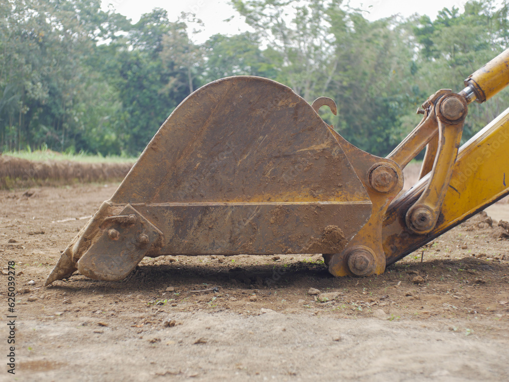 Backhoe working by digging soil at construction site. Bucket teeth of