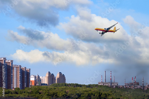 A cargo airliner delivers cargo to the city from the industrial zone. The concept of logistics delivery of goods from industrial regions with poor environmental conditions. Smoke from factories.