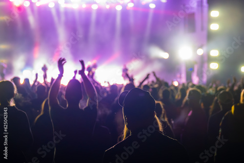 Unrecognizable crowd of people standing and clapping for artists performance on stage in live concert