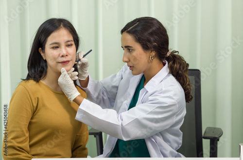 A professional healthcare provider is precisely performing a chin diagnosis procedure on a female patient in a sanitized, clinical environment. They are both focused on the process.