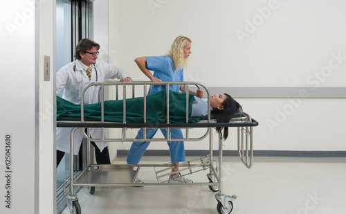 A nurse and doctor in propels a wheeled stretcher, carrying a patient through the sterile, well-lit hallway of a bustling hospital.