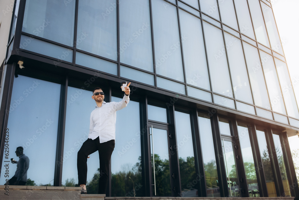 Conversation by phone. Business building behind. Man in suit and tie is standing near his car outdoors. Conversation by phone. Business building behind. Man in suit and tie is standing near his car outdoors.