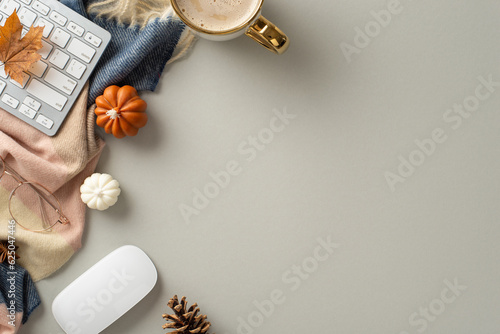 Autumn-themed workplace at home. Top view image of keyboard and mouse, gilded glasses, mug of coffee, scarf, pumpkin candles and maple foliage with space for promotion on grey isolated background
