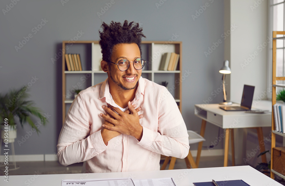 Fototapeta premium Smiling biracial man looking at screen having video call. Headshot portrait of young businessman making conference video call, having distant job interview, recording video blog