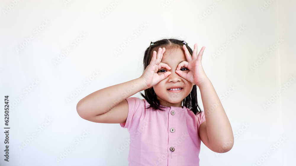 child seriously doing funny faces making with finger glasses shape like glasses looking through binoculars. isolated on light color background. child seriously doing funny faces making with finger glasses shape like glasses looking through binoculars. isolated on light color background.