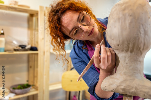 Tela Female sculptor working in pottery studio workshop sculpting human head