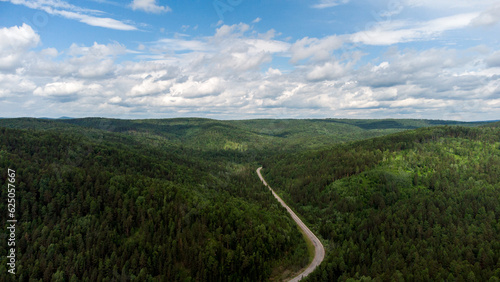 Aerial view of road through green forest. Wide angle