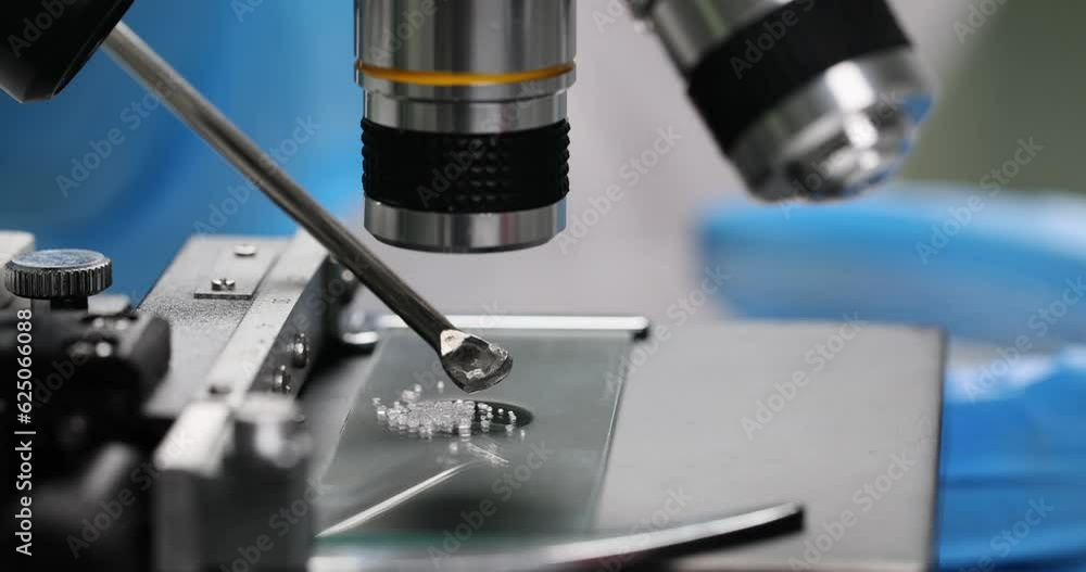 Specialist examines crystalline granules under microscope in laboratory. Scientist in rubber gloves does scientific research slow motion Specialist examines crystalline granules under microscope in laboratory. Scientist in rubber gloves does scientific research slow motion