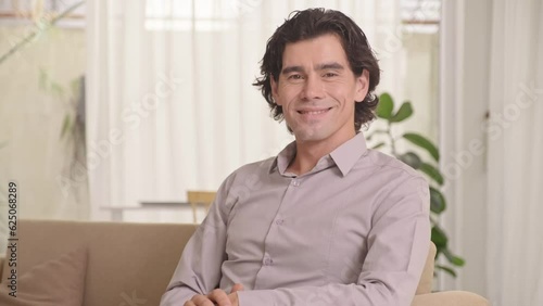 Tilt up portrait of young smiling businessman looking at camera while sitting indoors, suitable for face swap photo