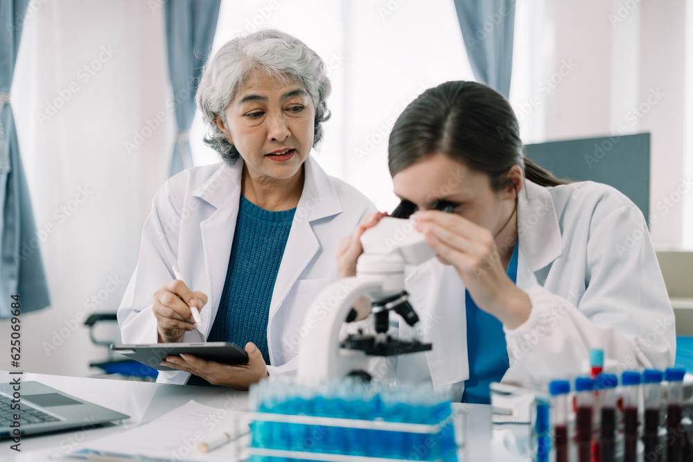 Team of biochemical research scientists working with a microscope for vaccine development in pharmaceutical research labeling. Team of biochemical research scientists working with a microscope for vaccine development in pharmaceutical research labeling.