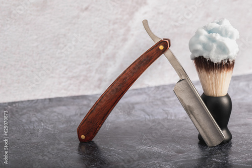 Shaving brush and straight razor on a concrete background.Selective focus. The concept of male self-care.