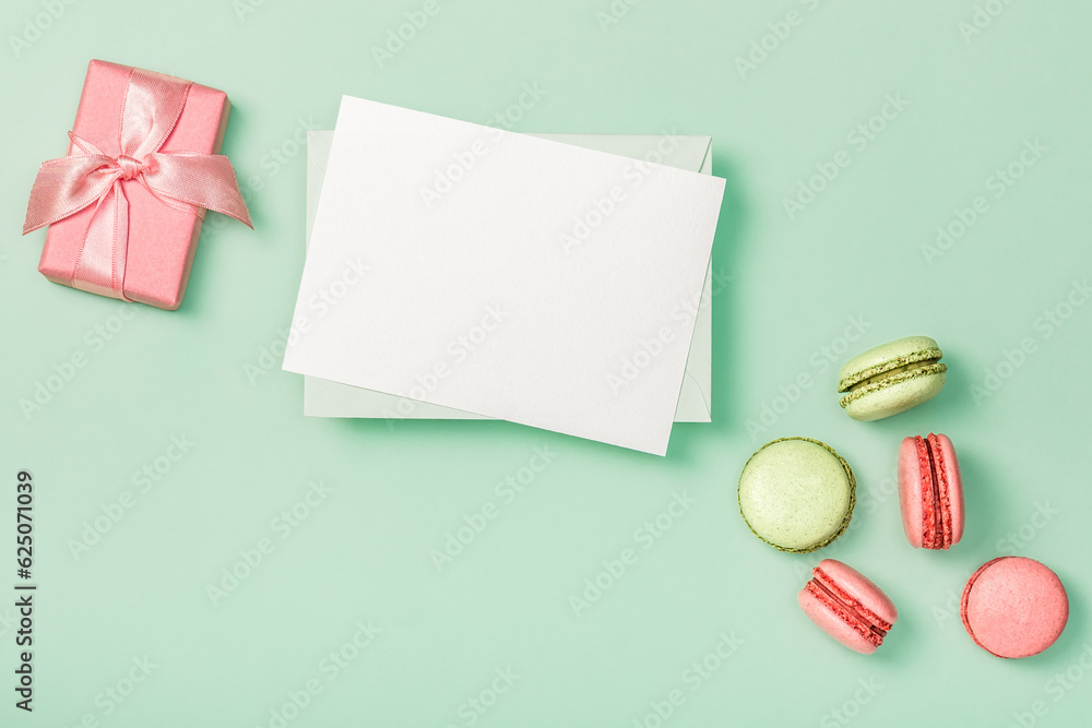Flat lay composition with blank empty, pink gift box and colorful macaroons on light green background. Greeting card. Invitation. Flat lay composition with blank empty, pink gift box and colorful macaroons on light green background. Greeting card. Invitation.