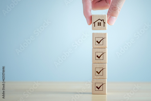 Checklist while buying your house. Hand holding house from stack that check mark are completed for home buying checklist. Refinance, home loan, tax, mortgage, buy, rent, property investment concept.