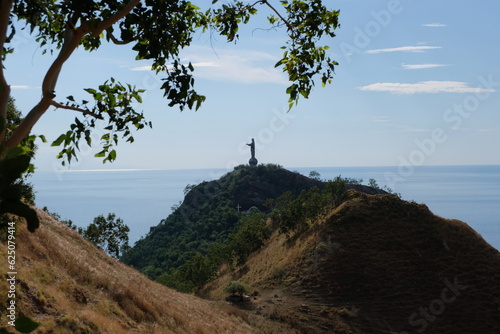 Popular tourism landmark of Cristo Rei statue atop rugged hilly landscape in capital city of Dili, East Timor, Southeast Asia