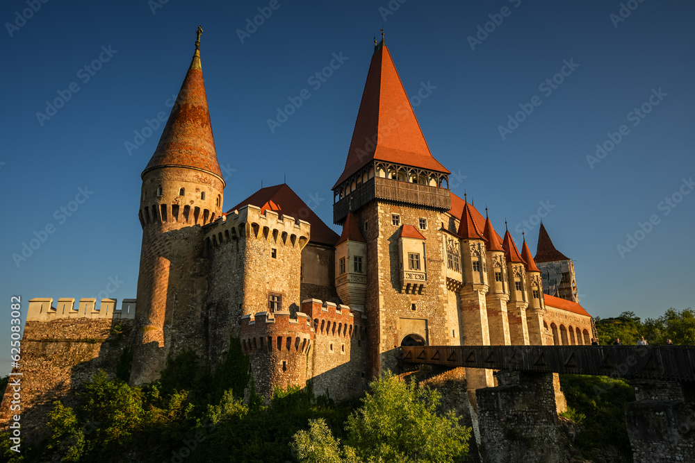 Corvin (Hunyad) Castle in Hunedoara during the sunset. Wide angle photo this amazing medieval castle landmark in Romania with the main river and bridge in foreground.