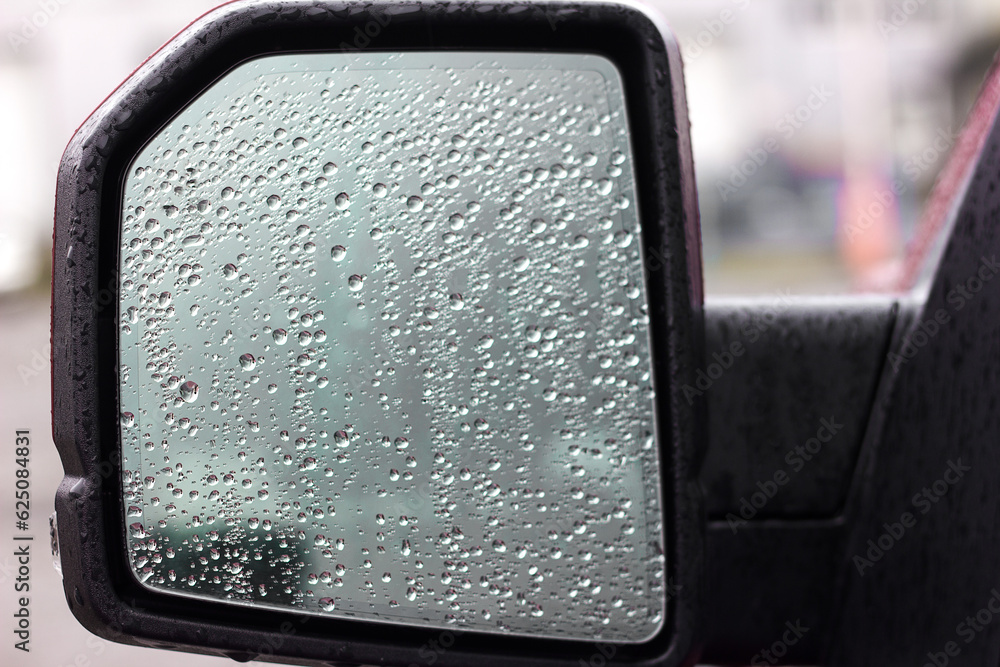 Raindrops on the side mirror of the car on the driver's side, the danger of driving in a car in rainy weather Raindrops on the side mirror of the car on the driver's side, the danger of driving in a car in rainy weather