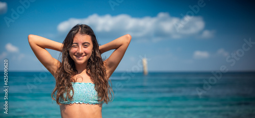 Happy beautiful young girl enjoys summer time at the beach