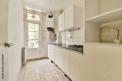 Fototapeta Naklejka Na Ścianę i Meble -  a kitchen with white cabinets and wood flooring in the middle part of the room, looking towards the window