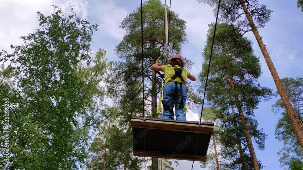 A 7-year-old Caucasian girl happily climbs an obstacle course in a rope park. A 7-year-old Caucasian girl happily climbs an obstacle course in a rope park.