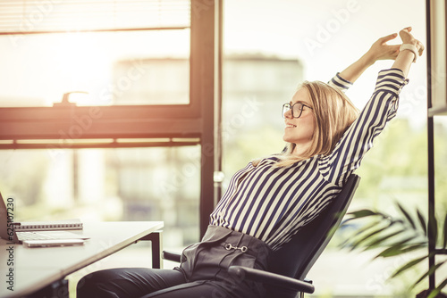 End of working day. Relax in the office in the glow of the setting sun. Happy woman office worker.