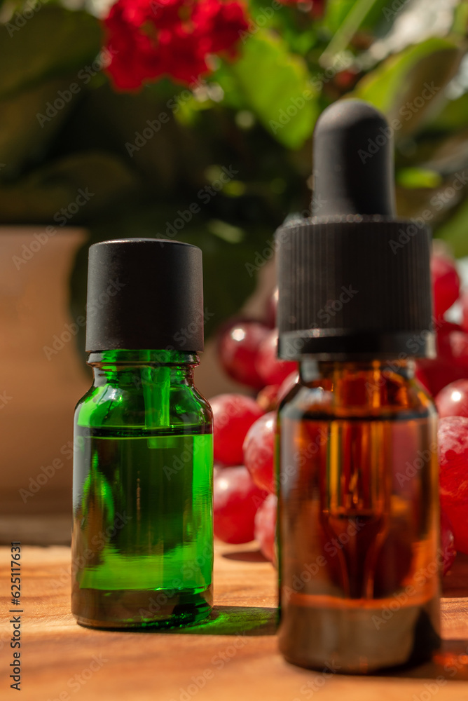 Brown and green bottles of essential oils. natural cosmetics for skin care. Bottles with an eyedropper, grapes and flowers on a wooden table. Taking care of health and beauty. Brown and green bottles of essential oils. natural cosmetics for skin care. Bottles with an eyedropper, grapes and flowers on a wooden table. Taking care of health and beauty.