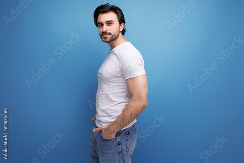 stylish bearded brunette man in white t-shirt on studio background with copyspace