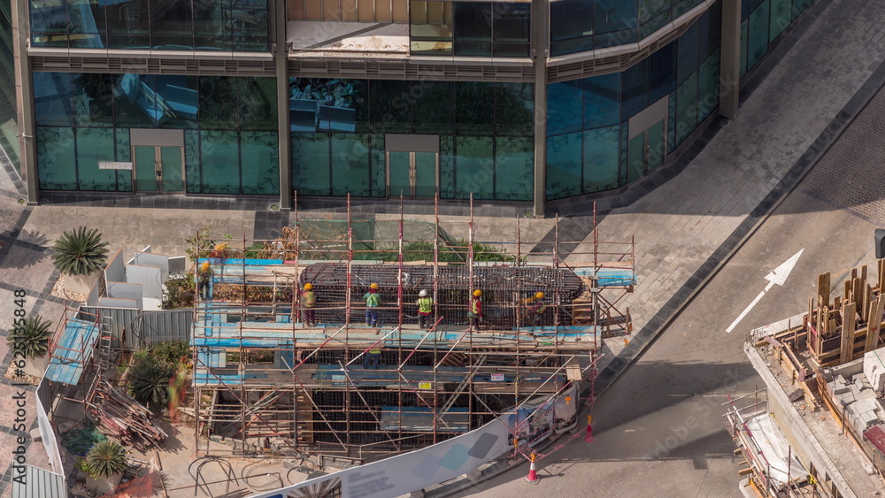 Many workers on the construction site making reinforcement metal framework for concrete pouring aerial timelapse