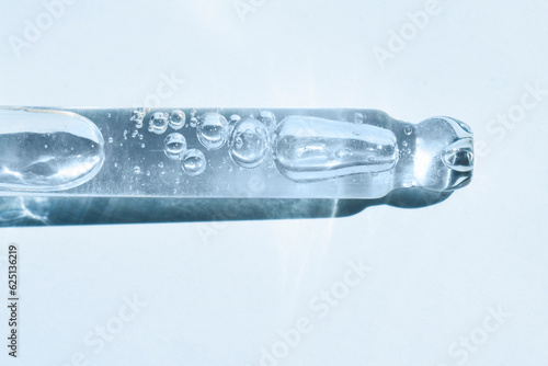 Pipette with a means for moisturizing and skin care on a blue background, top view. Recovery procedures, beauty concept.