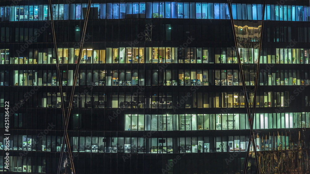 Frontal view of night facade of building with a lot of windows with light timelapse.