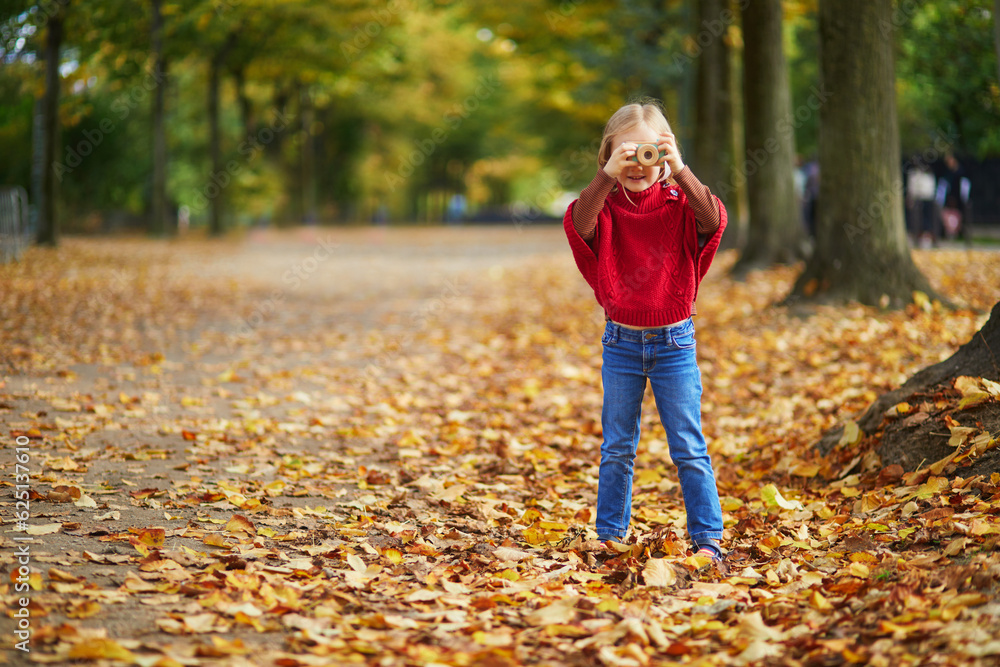 Adorable preschooler girl taking a photo with wooden toy camera in autumn park in Paris, France Adorable preschooler girl taking a photo with wooden toy camera in autumn park in Paris, France