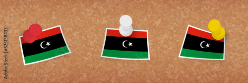 Libya flag pinned in cork board, three versions of Libya flag.