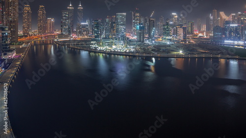 Fototapeta Naklejka Na Ścianę i Meble -  Cityscape with skyscrapers of Dubai Business Bay and water canal aerial night timelapse.