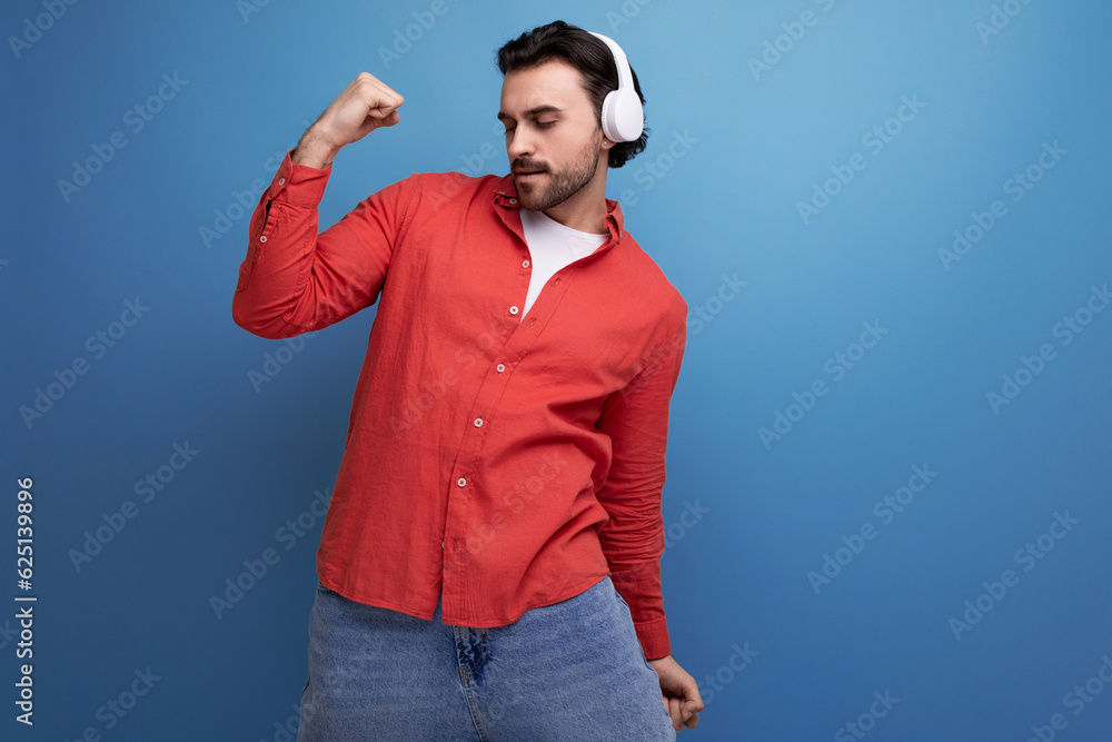 a handsome young guy with gorgeous black hair listens to music on headphones and dances a handsome young guy with gorgeous black hair listens to music on headphones and dances