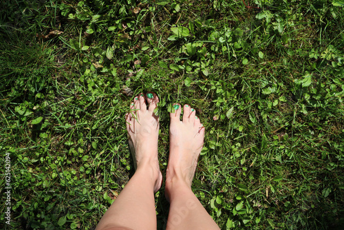 Bare female feet on a green grass.