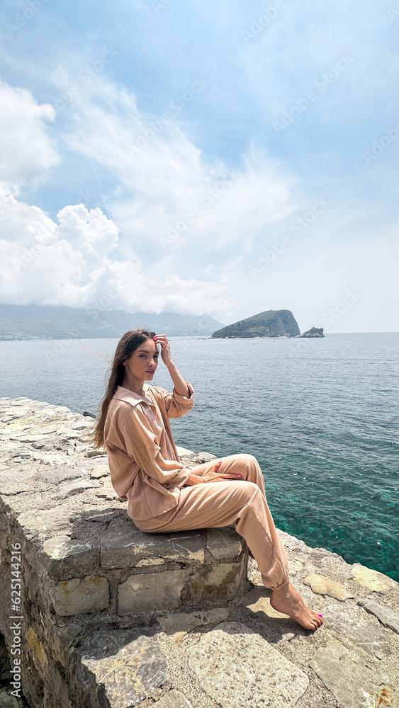 Beautiful woman sits on the rock at the sea