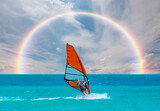 Young girl surfing the wind in splashes of water amazing rainbow in the background - Alacati, Cesme