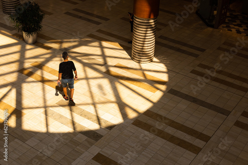 Foto High angle back view of man in casual summer clothes walking in circle of light