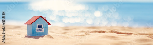 Miniature model of a house standing on the sand on the seacoast.