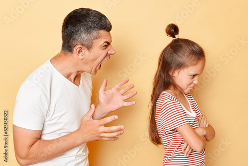 Foto Father punishing his daughter, domestic violence, young man screaming on little girl with aggression and anger standing isolated over beige background