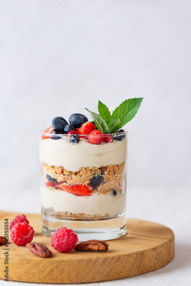 Vegan trifle dessert in a glass with berries, mint, whipped cream and biscuit on a wooden board. Healthy food, sugar, gluten and lactose free. Vegan trifle dessert in a glass with berries, mint, whipped cream and biscuit on a wooden board. Healthy food, sugar, gluten and lactose free.