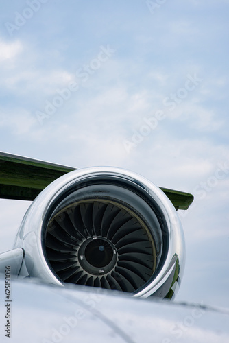 Close-up of a jet engine turbine under the wing of a modern aircraft against a cloudy sky
