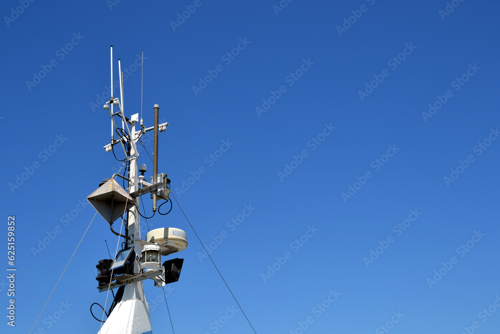 Fishing boat mast with radar, light and navigation system elements. Blue sky backgorund Fishing boat mast with radar, light and navigation system elements. Blue sky backgorund