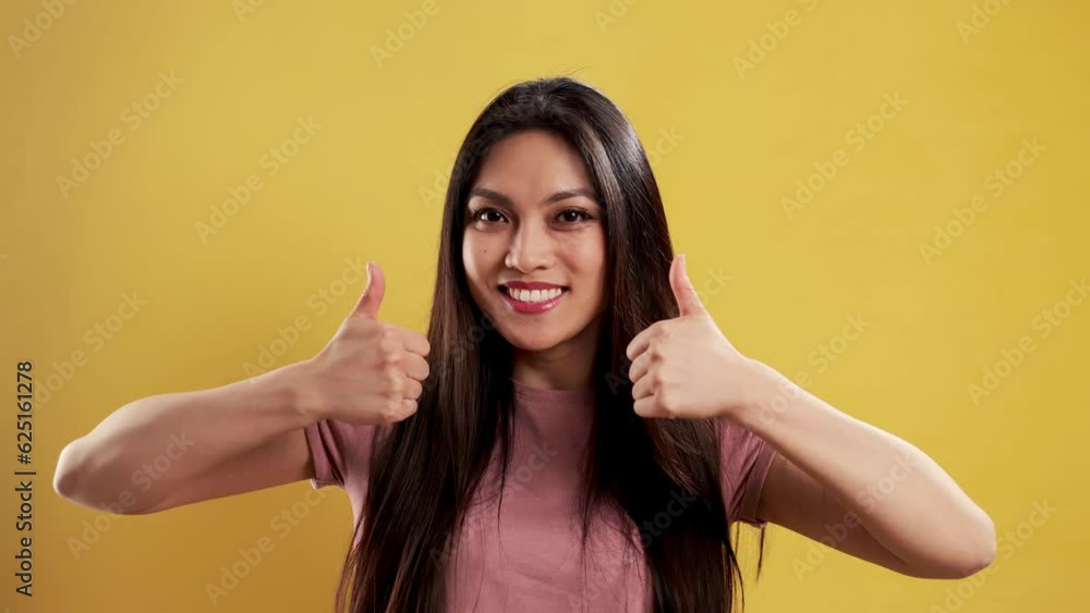 Asian Girl with a confident smile in a studio doing a thumbs up gesture - extreme slow motion shot Asian Girl with a confident smile in a studio doing a thumbs up gesture - extreme slow motion shot