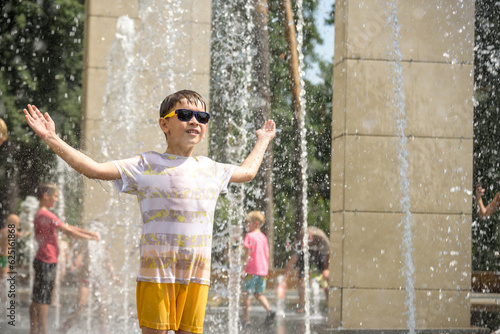 Boy having fun in water fountains. Child playing with a city fountain on hot summer day. Happy kids having fun in fountain. Summer weather. Active leisure, lifestyle and vacation