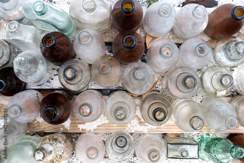 overhead shot of empty uncapped bottles on wooden plank with white sand scattered all over it photo
